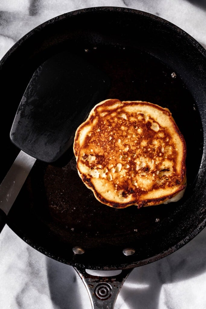 golden brown cooked banana pancake flipped in nonstick pan.