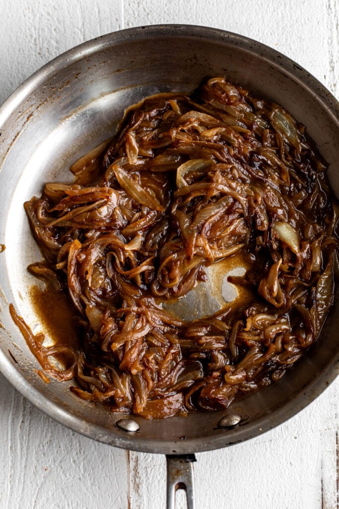 Guinness beer caramelized onion in silver sauté pan.