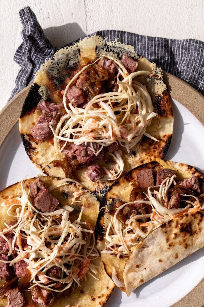 irish-inspired corned beef tacos with creamy cabbage slaw and guinness caramelized onions.