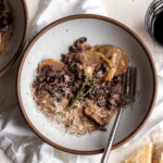 creamy mushroom ragu sauce with short rib ravioli with thyme sprig and parmesan.
