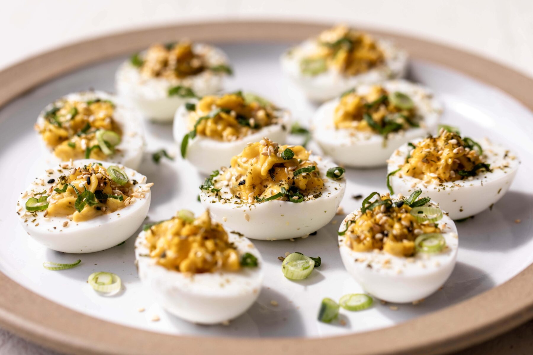 yuzu kosho deviled eggs topped with furikake and diced green onions.