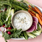 Finished bed cheese dip with fresh vegetables on plate.