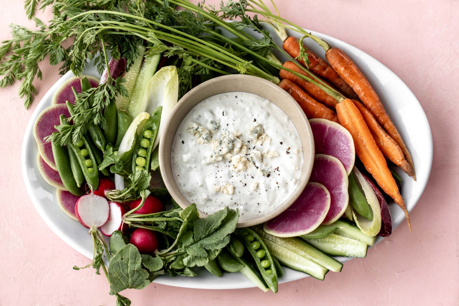 Finished bed cheese dip with fresh vegetables on plate.