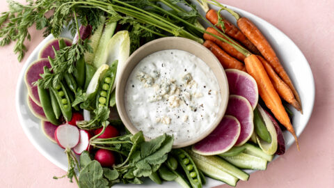 Finished bed cheese dip with fresh vegetables on plate.