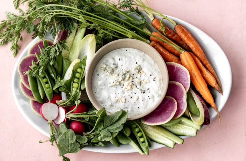 Finished bed cheese dip with fresh vegetables on plate.