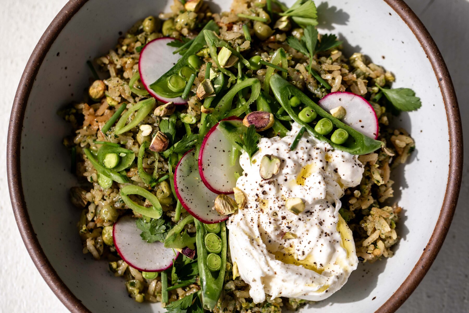 Green spring rice pilaf with pistachio and pesto burrata ready for serving.
