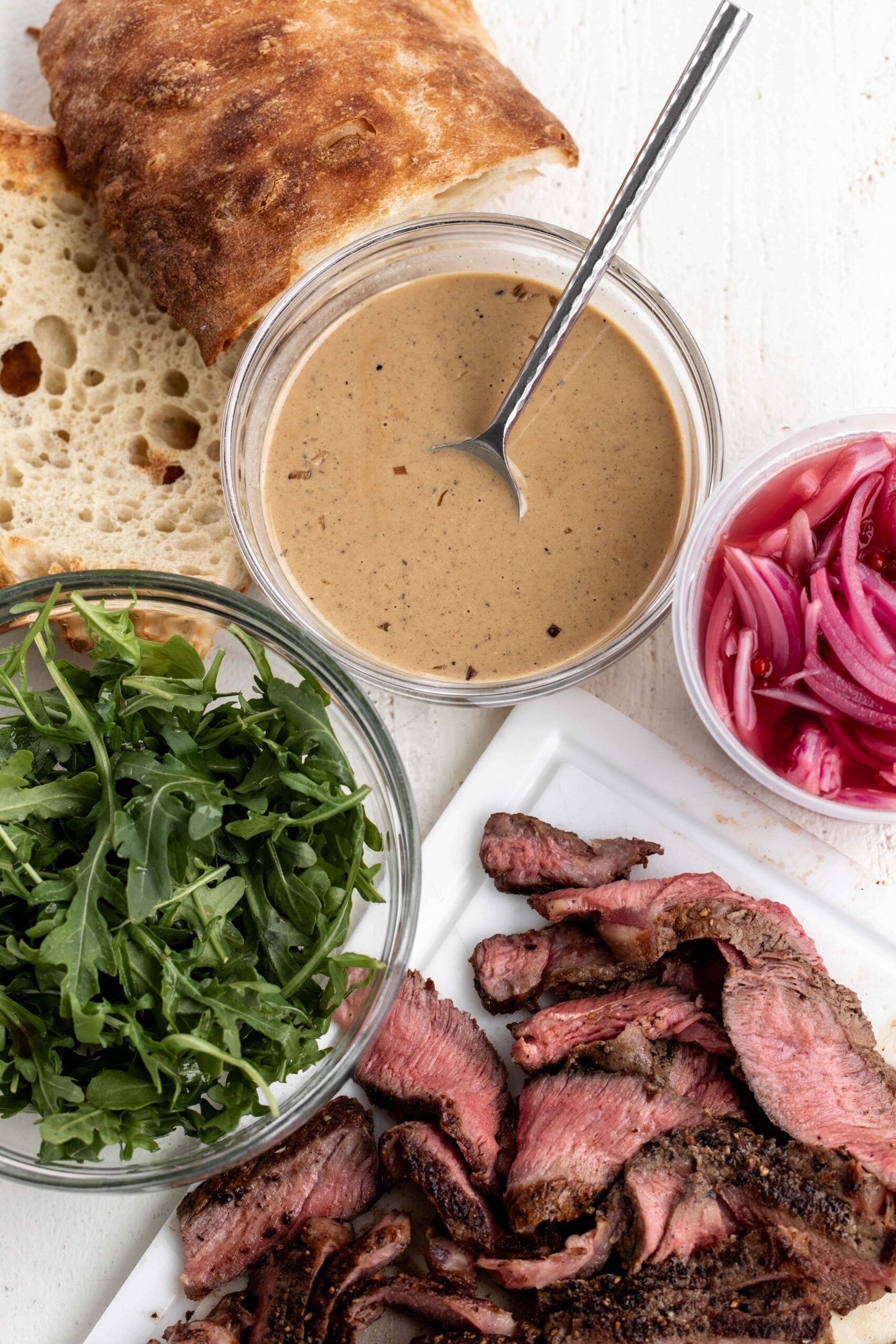Au Poivre sauce with cooked steak, pickled onions and arugula. 