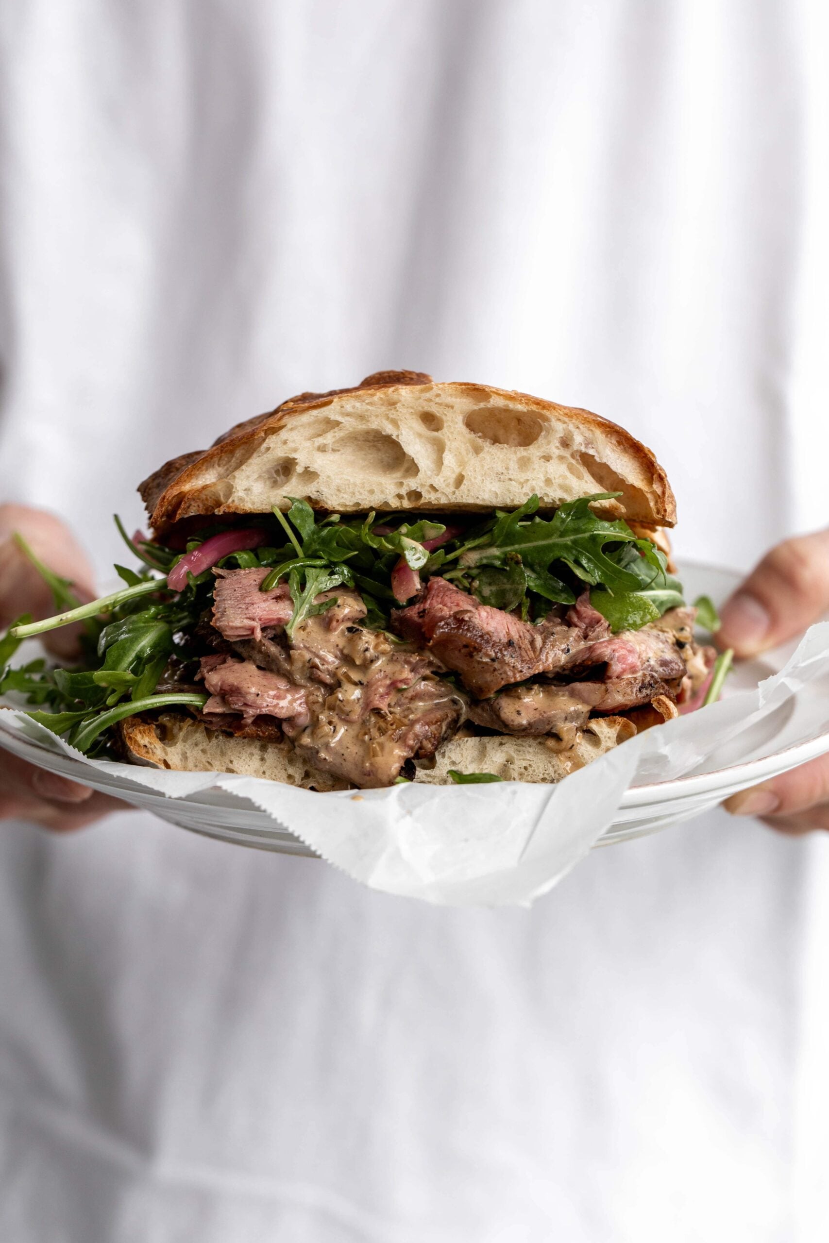 Finished steak au poivre sandwich with arugula on ciabatta bread. 