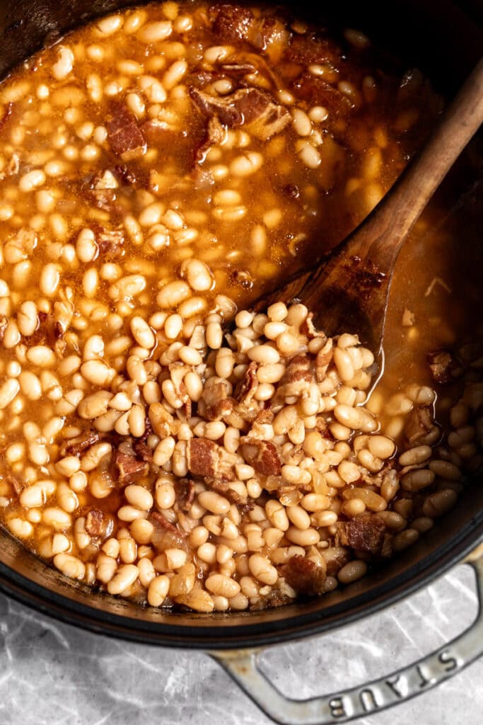 cooked beans in pot with wooden spoon.