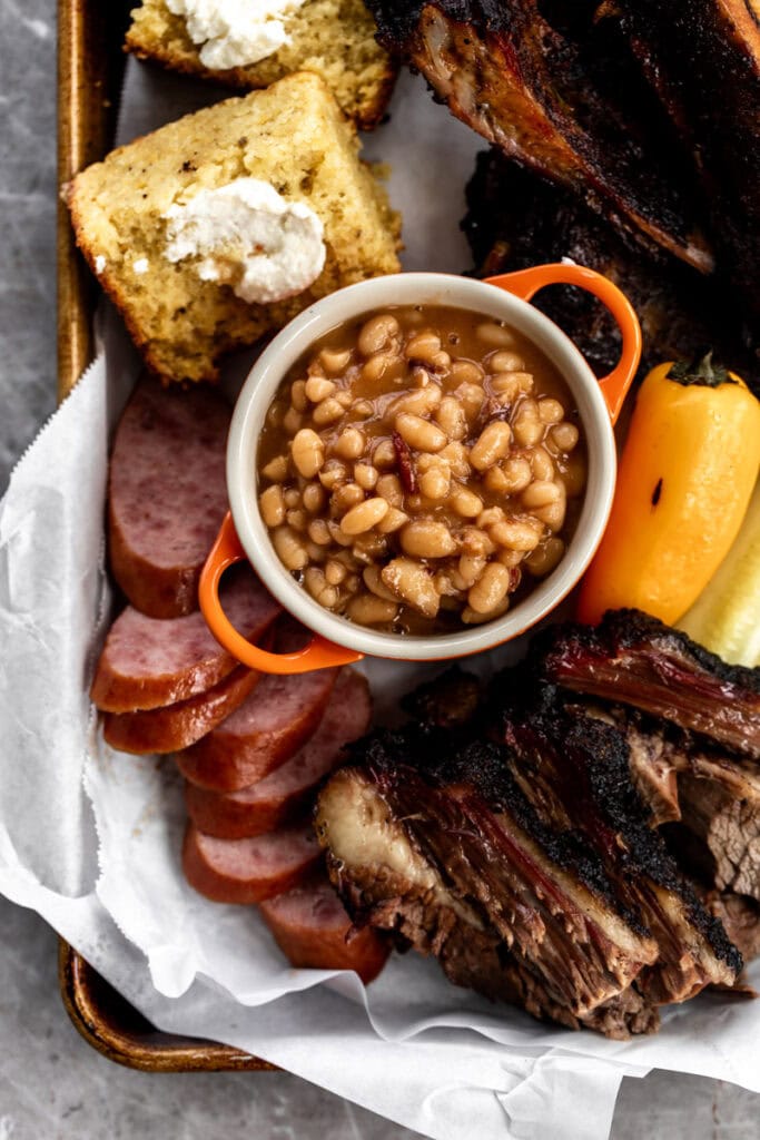 best baked beans recipe in small pot with bbq ribs cornbread and brisket.