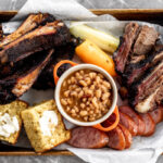 best baked beans recipe in small pot with bbq ribs cornbread and brisket.