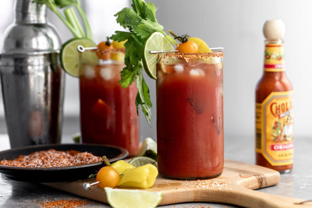 mezcal bloody maria garnished with celery, toamto and lime wedges.