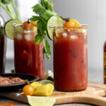 mezcal bloody maria garnished with celery, toamto and lime wedges.