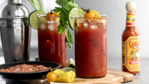 mezcal bloody maria garnished with celery, toamto and lime wedges.