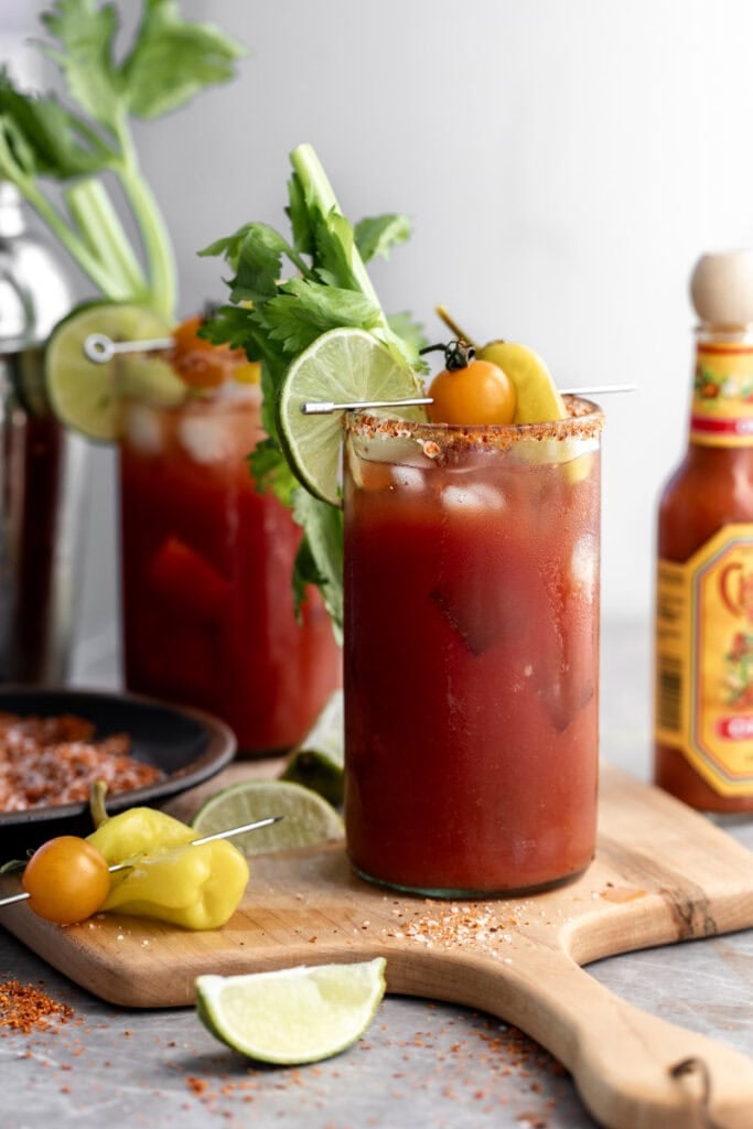 mezcal bloody maria garnished with celery, toamto and lime wedges.