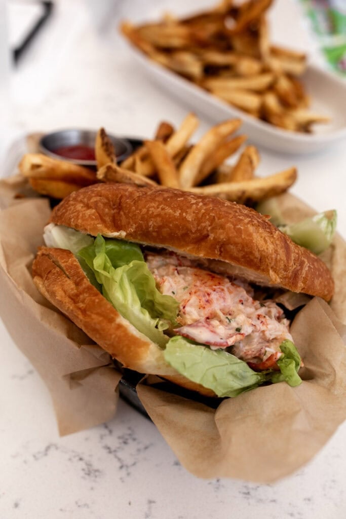 lobster salad on roll with butter lettuce and fries.