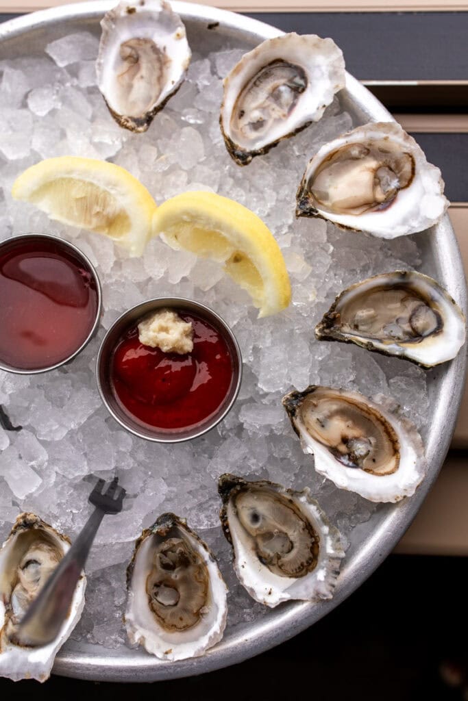 oysters on the half shell on ice with lemon wedges.