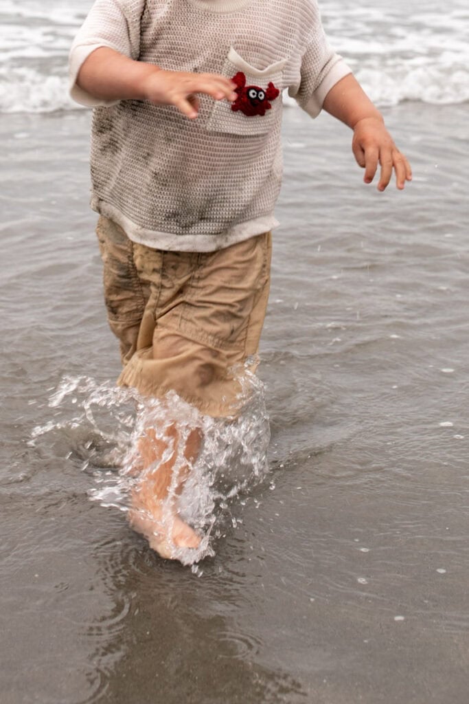 kid running through water at the beach.