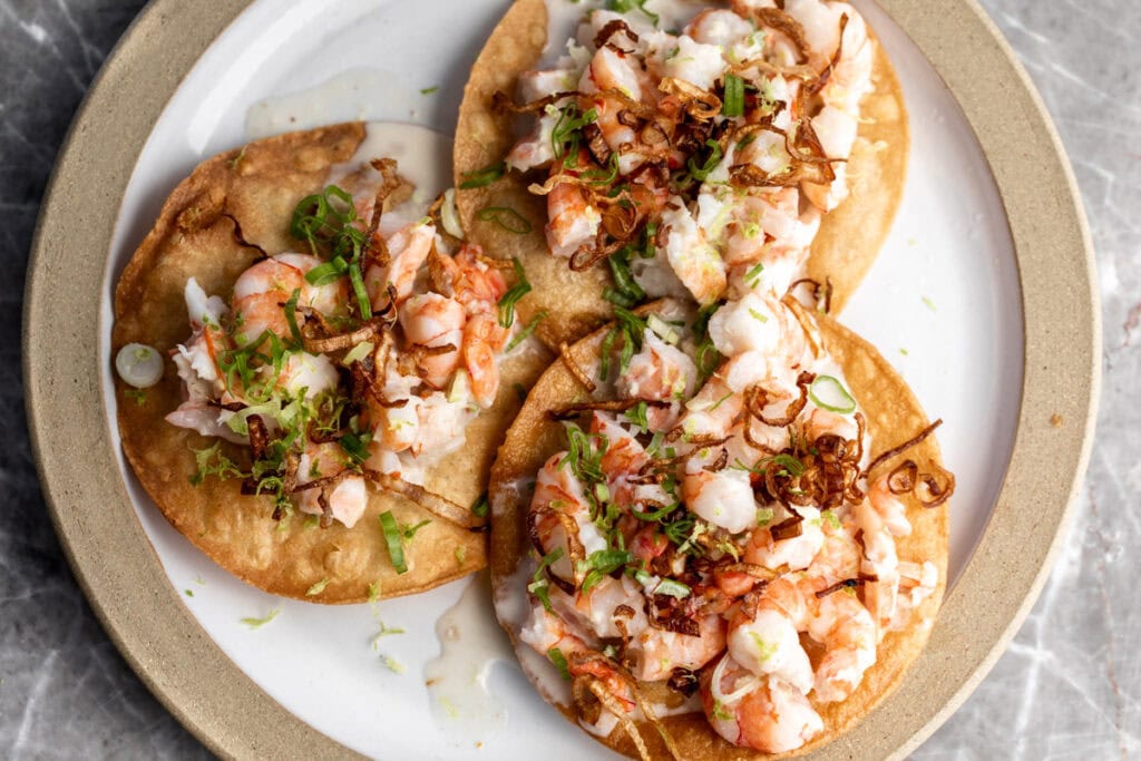 coconut shrimp ceviche tostadas with crispy fried shallots garnished with lime zest.