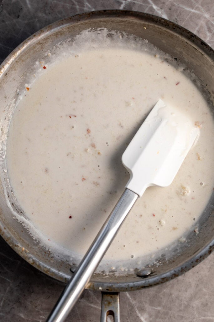 coconut cream sauce in sauté pan with white spatula.