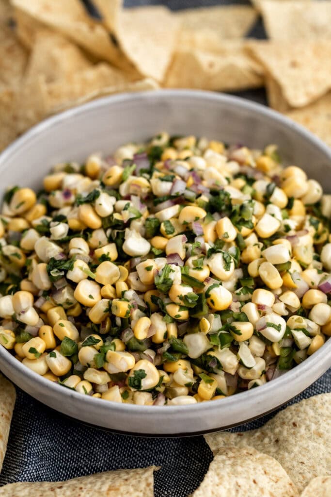 fresh corn salsa recipe in bowl with tortilla chips.