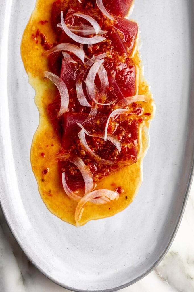 orange calabrian chili tuna crudo topped with shaved onion.