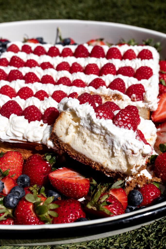 red white and blue flag cheesecake with berries and whipped cream slice closeup.