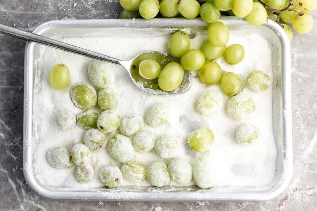 sour candied grapes on baking sheet in sugar.