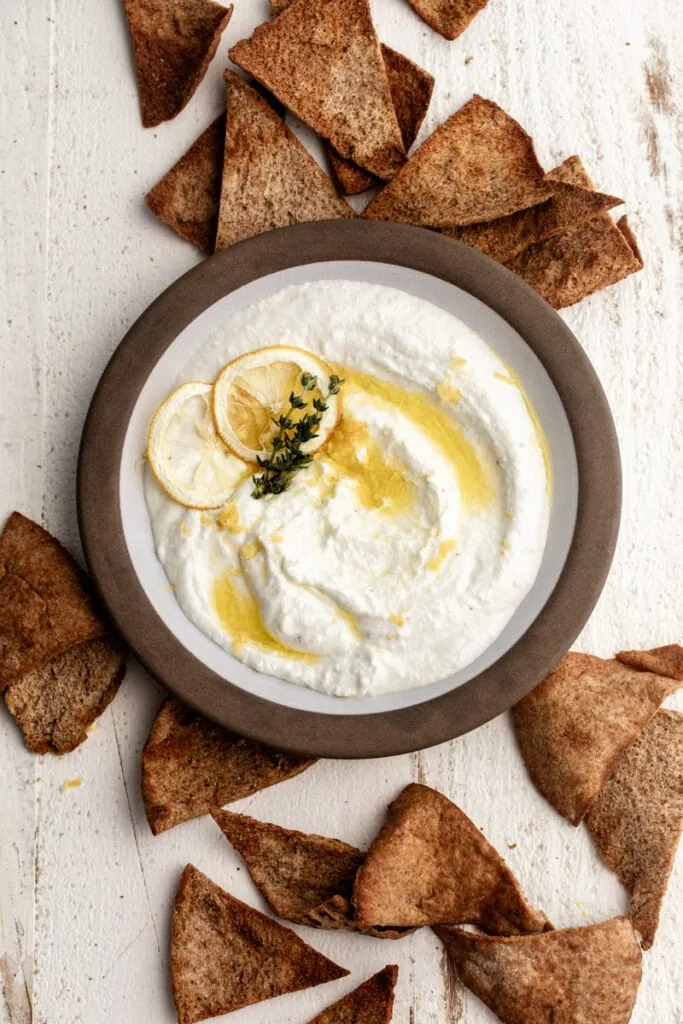served dip in ceramic bowl with crispy pita chips.