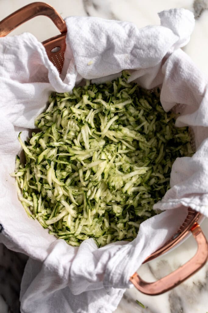 drained grated zucchini in copper colander.
