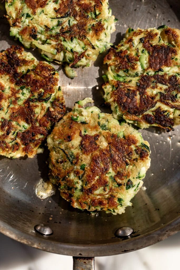 zucchini fritters cooked in sauté pan.