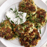 zucchini fritters with lemon yogurt sauce garnished with chopped chives and dill.