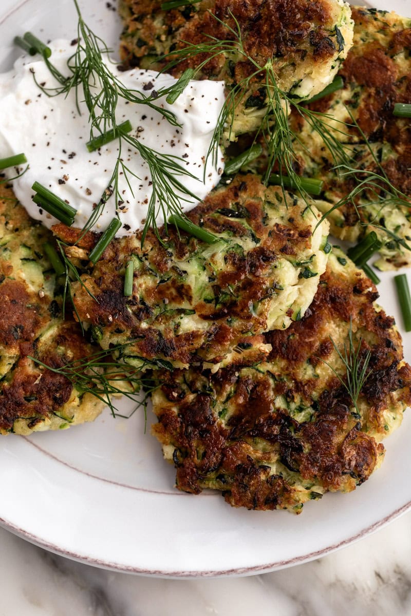 zucchini fritters with lemon yogurt sauce garnished with chopped chives and dill.