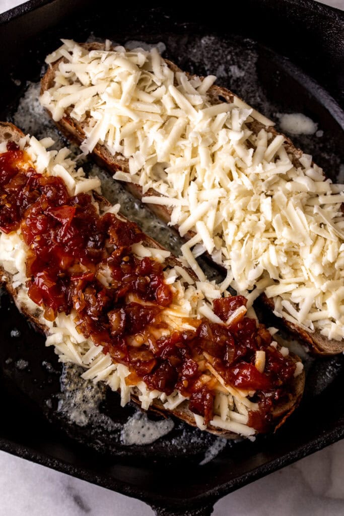 slices of sourdough bread topped with shredded cheese and tomato bacon jam.