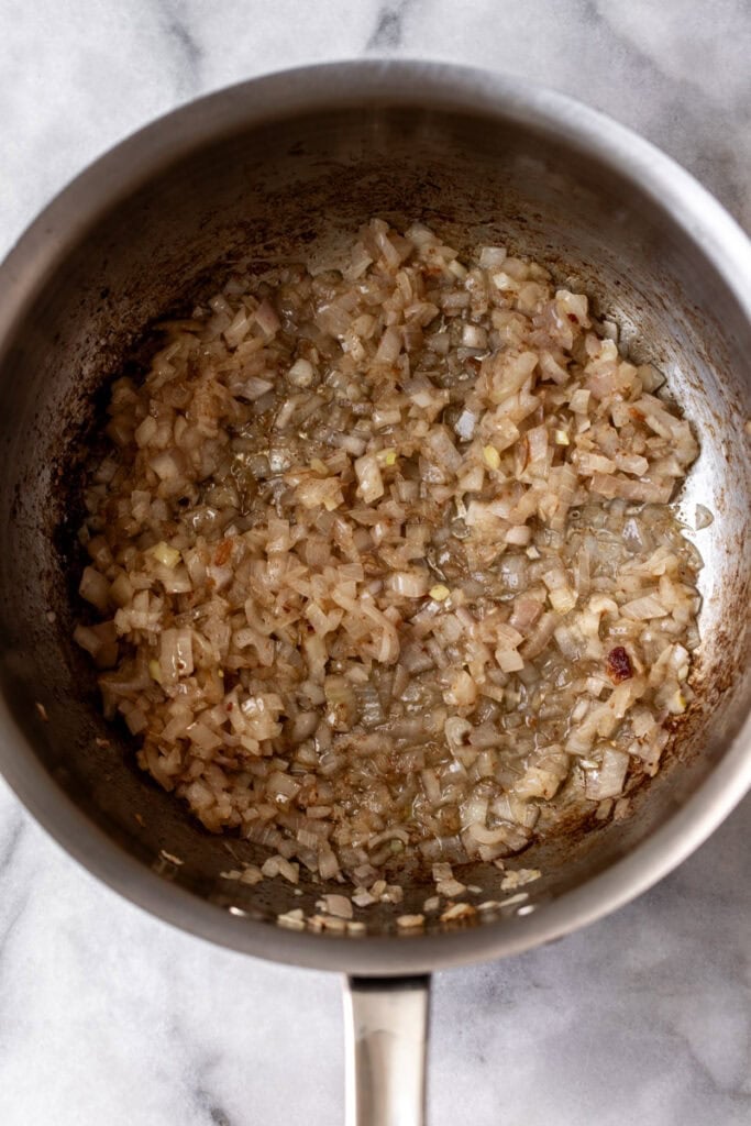 diced onions in sauté pan for tomato bacon jam.