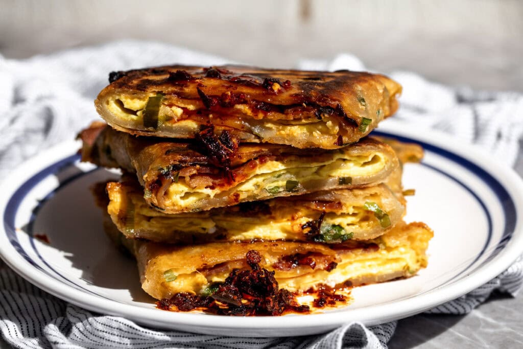 scallion pancake bacon egg and cheese sandwich with a drizzle of chili crisp.