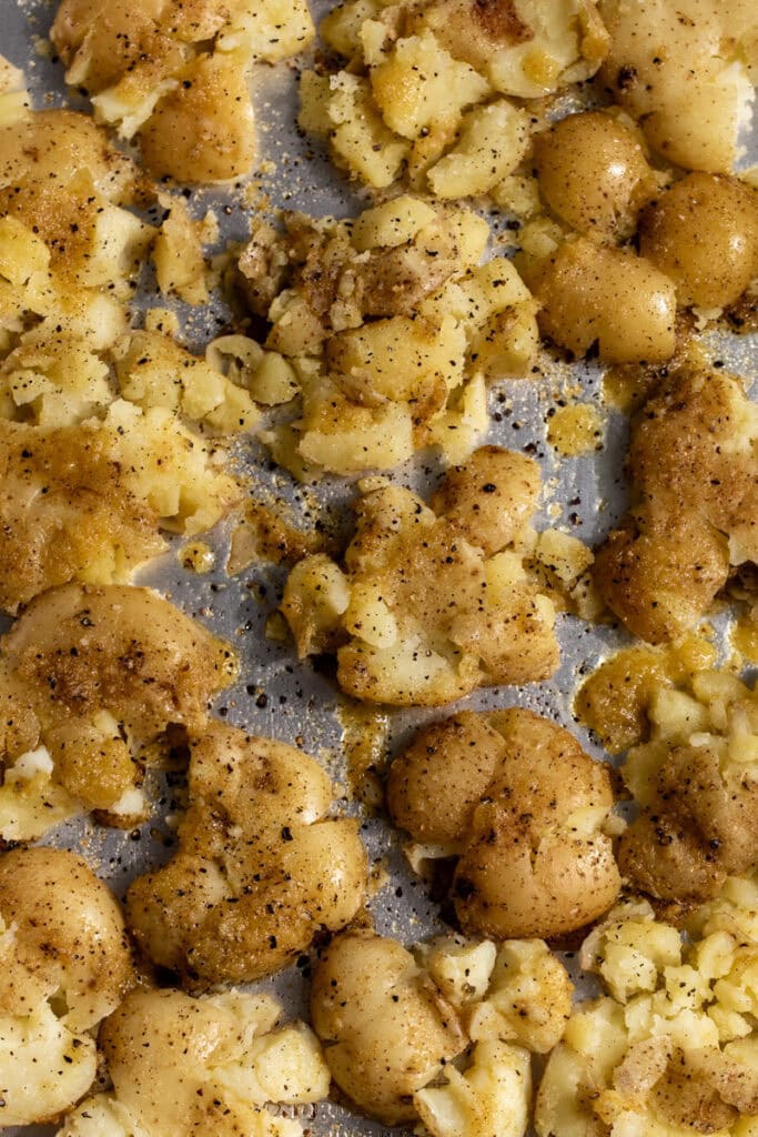 smashed potatoes on baking sheet seasoned with salt and pepper.