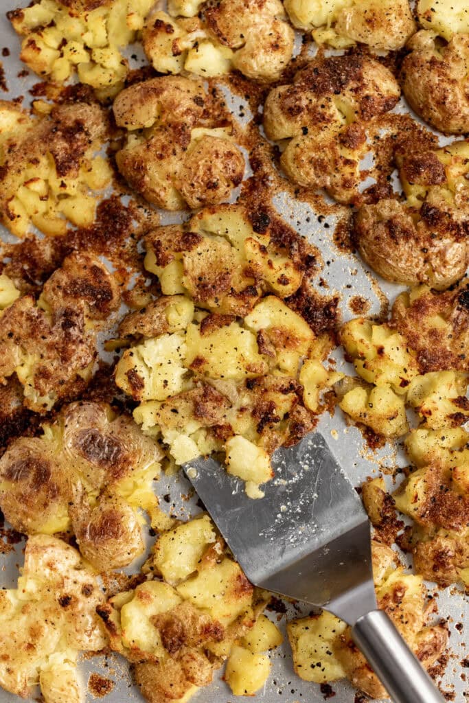 sour cream and onion crispy potatoes - in photo: roasted potatoes on sheet pan with metal spatula.