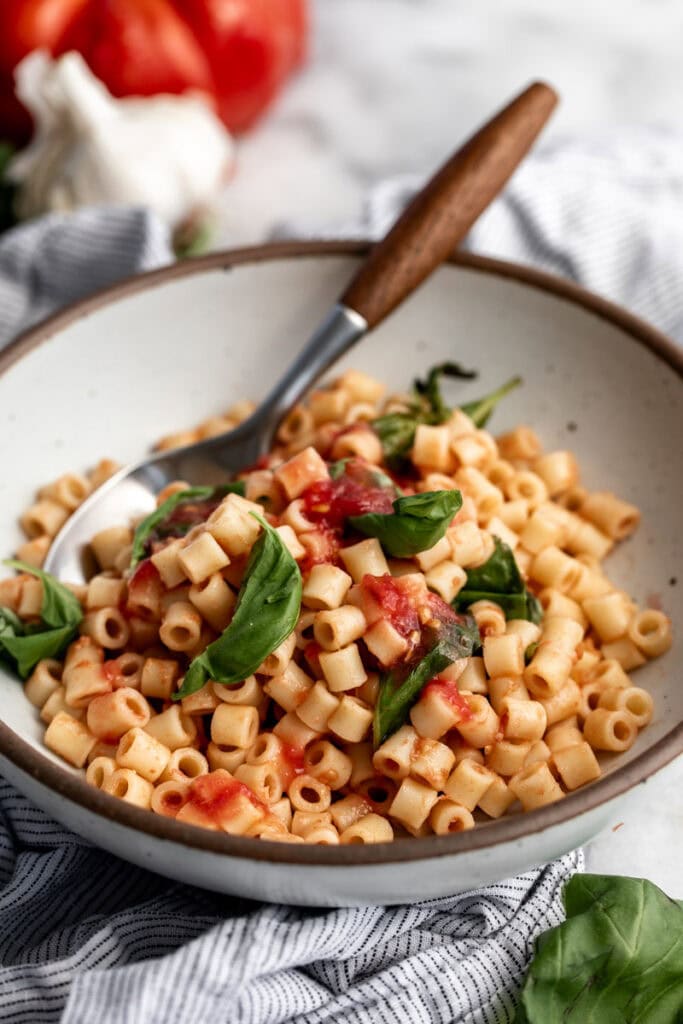 4 ingredient no cook easy tomato sauce over ditalini with basil leaves.
