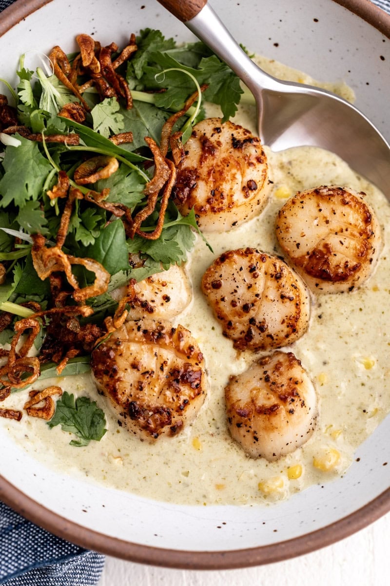 Green Curry Scallops with Corn topped with cilantro herb salad and fried crispy shallots.