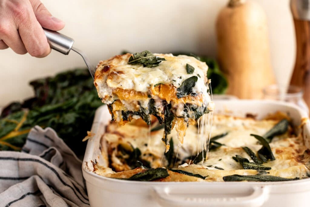 Lifting up butternut squash lasagna with spatula.