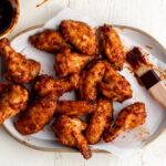 maple chipotle chicken wings on parchment paper with brush.