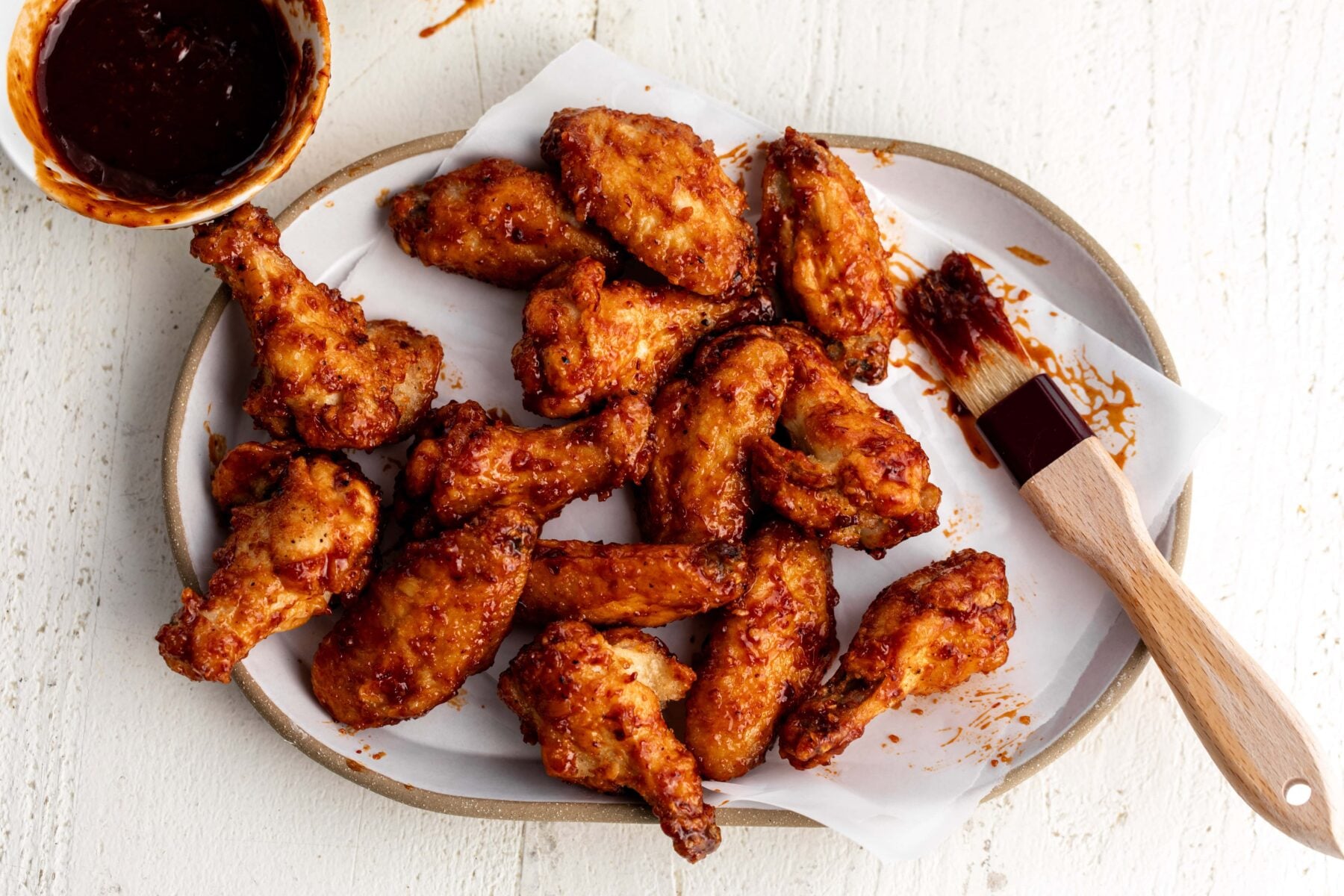 maple chipotle chicken wings on parchment paper with brush.