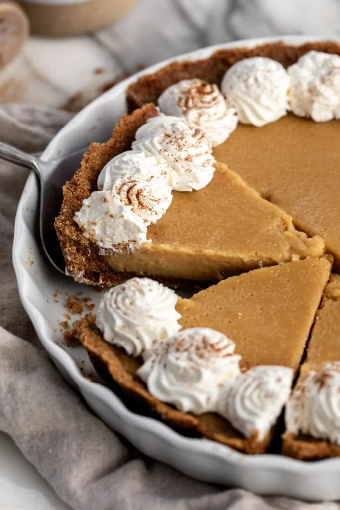 maple cream pie sliced in baking dish garnished with whipped cream.