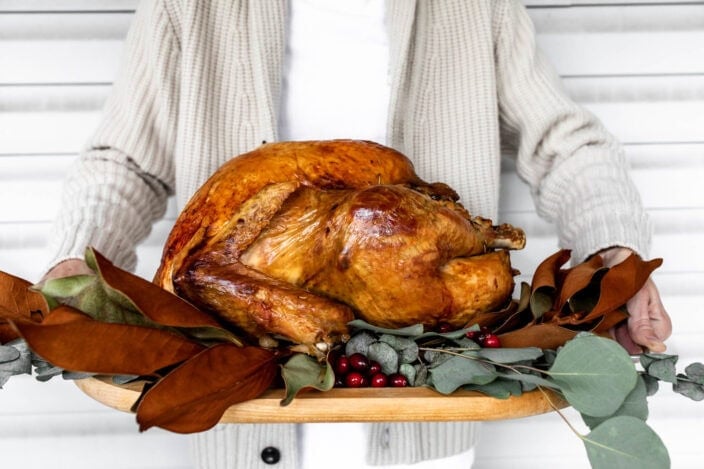 herb brined thanksgiving turkey roasted golden brown on cutting board.