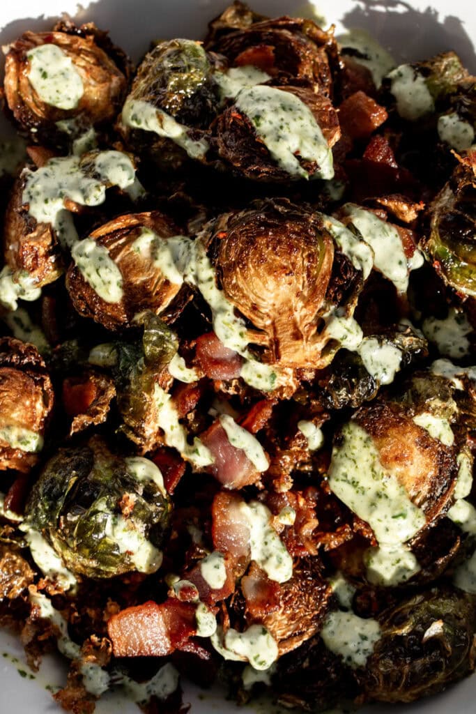 fried kimchi brussels sprouts with bacon and cilantro sauce drizzled over top.