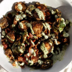 fried kimchi brussels sprouts with bacon and cilantro sauce drizzled over top.