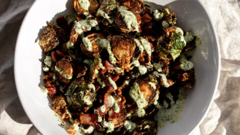 fried kimchi brussels sprouts with bacon and cilantro sauce drizzled over top.