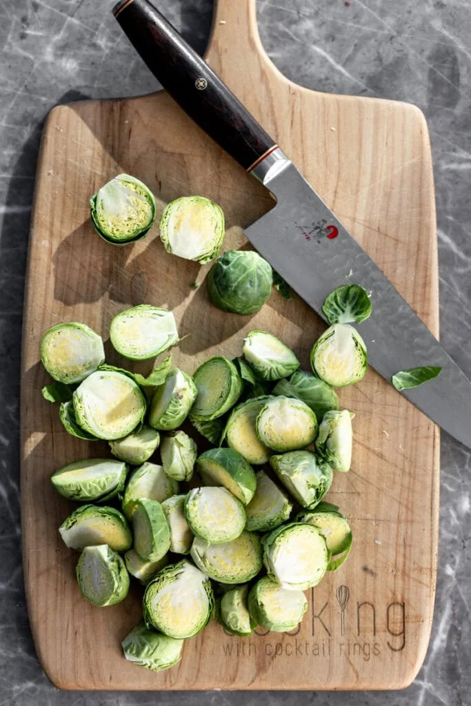 halved brussels sprouts on cutting board with knife.