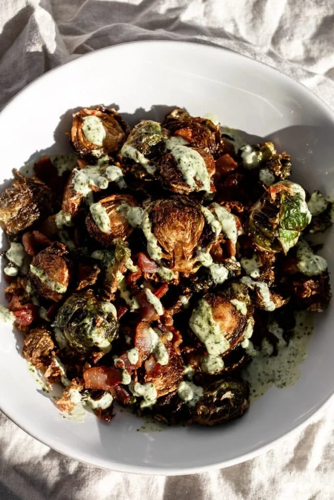 fried kimchi brussels sprouts with bacon and cilantro sauce drizzled.